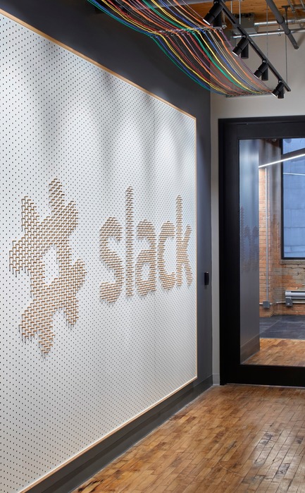 Press kit | 1513-01 - Press release | Slack Toronto Office - Dubbeldam Architecture + Design - Commercial Interior Design -  Opposite the elevator, a pegboard fabricated by local Atelier Kozak greets guests with company slogans and logos. It can be reorganized by employees, inviting playfulness and creativity.<br>  - Photo credit: Shai Gil