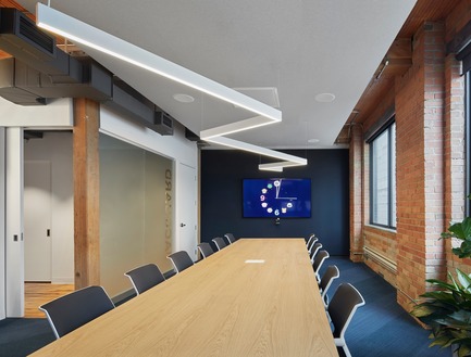 Press kit | 1513-01 - Press release | Slack Toronto Office - Dubbeldam Architecture + Design - Commercial Interior Design - The elegant oak table by Vitra adds warmth to the executive boardroom. A dropped ceiling over the table conceals technical equipment for various teleconferencing functions, and provides greater acoustic performance. The same angular light fixture threads through the room as an allusion to the continuous lines found throughout the office.  - Photo credit: Shai Gil