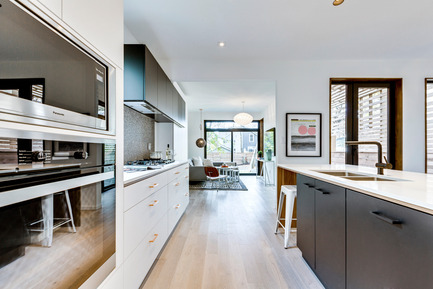 Press kit | 2344-01 - Press release | 46H - Sustainable Reinvention of 1905 House in the Beaches - baukultur/ca - Residential Architecture - Kitchen looking towards Family Room in Rear of House: Kitchen cabinets with white & black extra matt surfaces in combination with walnut detailing and copper pulls<br><br> - Photo credit: SilverHouse