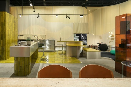 Press kit | 2704-05 - Press release | “Das Haus” 2019 at the imm cologne: Living by moods creates an appetite for open-plan homes - imm cologne 2019, Koelnmesse GmbH - Residential Interior Design - The Active zone of the Das Haus 2019 installation that Studio Truly Truly designed for imm cologne is dominated by clear lines and stimulating colours, with gleaming surfaces that reflect the bright lighting. The lime green tiles (Made a Mano), stainless steel kitchen blocks and Kvadrat curtain surrounding Das Haus add up to a highly distinctive character. - Photo credit: Constantin Meyer; Koelnmesse